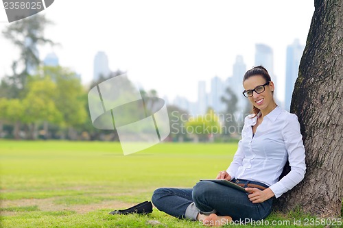 Image of Beautiful young woman with  tablet in park