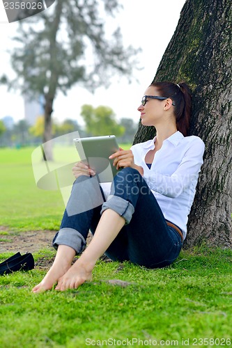 Image of Beautiful young woman with  tablet in park