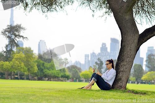 Image of Beautiful young woman with  tablet in park
