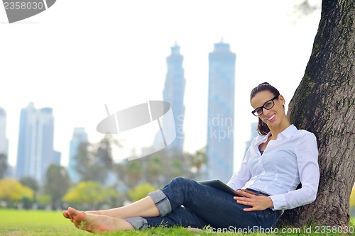 Image of Beautiful young woman with  tablet in park