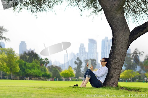 Image of Beautiful young woman with  tablet in park