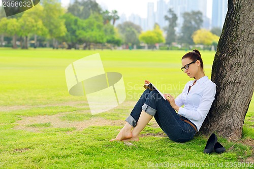 Image of Young woman reading a book in the park