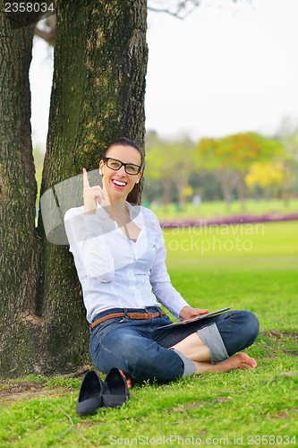 Image of Beautiful young woman with  tablet in park