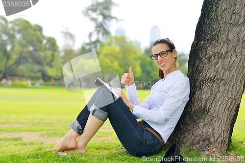 Image of Young woman reading a book in the park