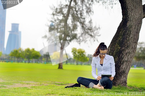 Image of Beautiful young woman with  tablet in park