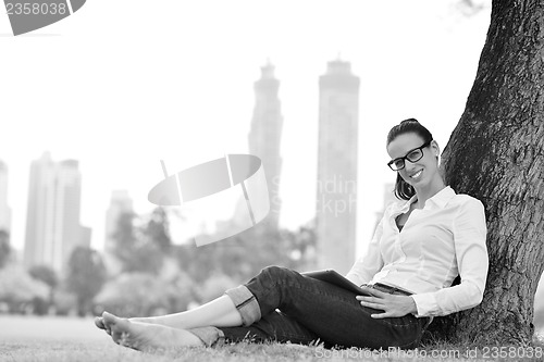 Image of Beautiful young woman with  tablet in park