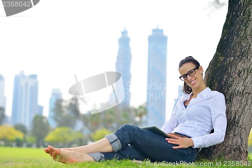 Image of Beautiful young woman with  tablet in park