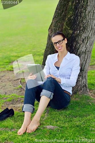 Image of Beautiful young woman with  tablet in park