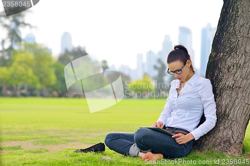 Image of Beautiful young woman with  tablet in park