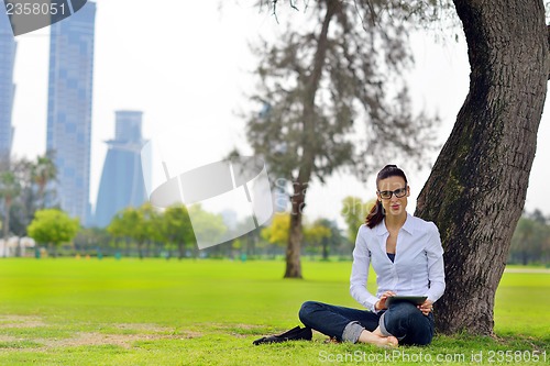 Image of Beautiful young woman with  tablet in park
