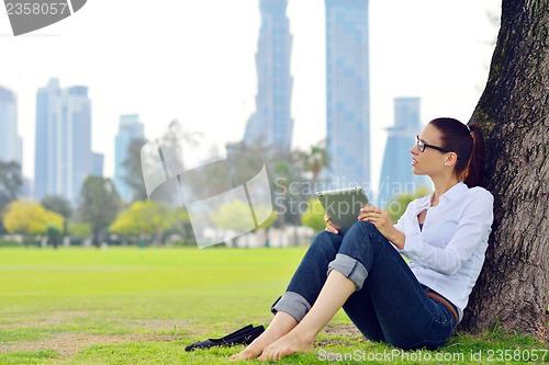 Image of Beautiful young woman with  tablet in park