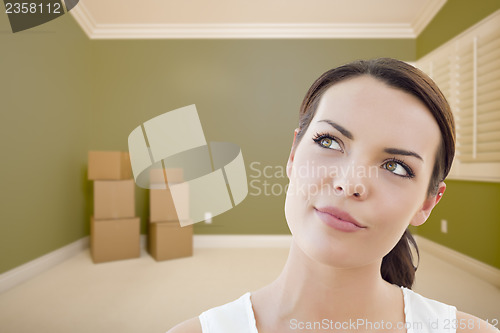 Image of Young Woman Daydreaming in Empty Room with Boxes