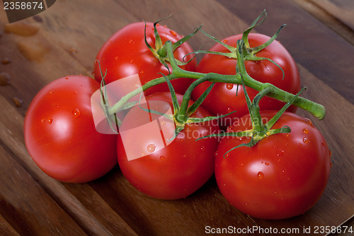 Image of Bunch of fresh tomatoes with water drops on wooden table