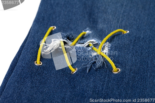 Image of Blue jean with hole and crisscross yellow lacing