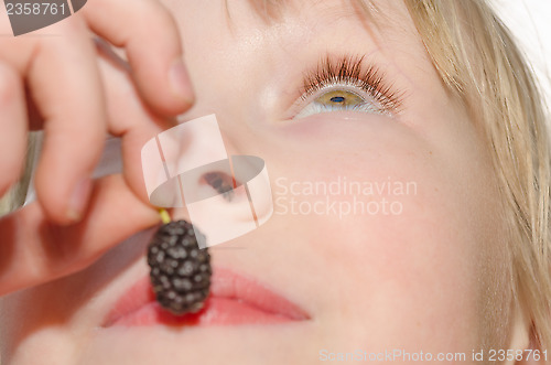 Image of Girl holding and eating mulberry fruit