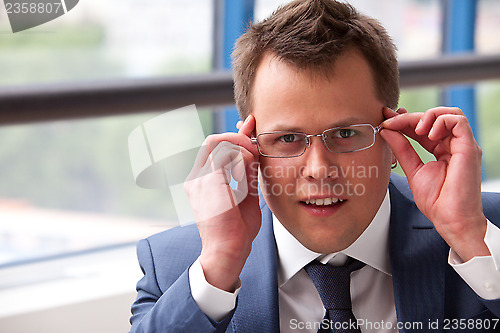 Image of businessman adjusts his glasses