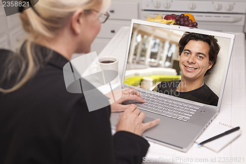 Image of Woman In Kitchen Using Laptop Online Dating Search