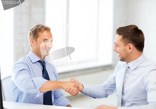 Image of businessmen shaking hands in office