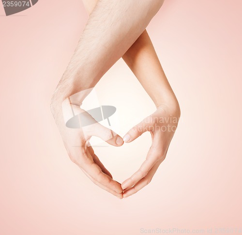 Image of woman and man hands showing heart shape