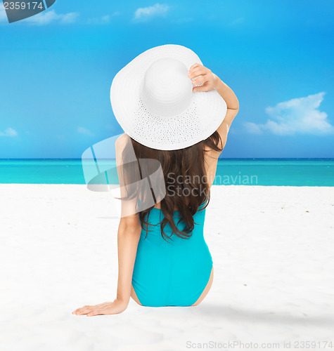 Image of model sitting in swimsuit with hat