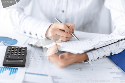 Image of woman hand with calculator and papers