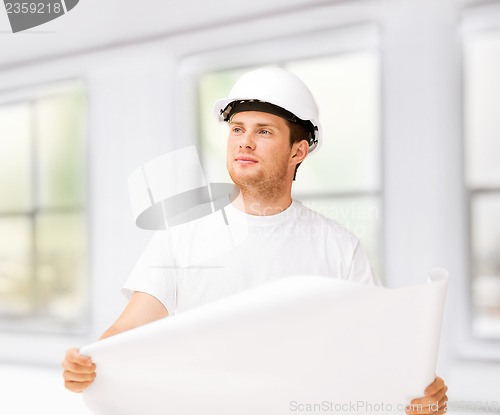 Image of male architect looking at blueprint at home