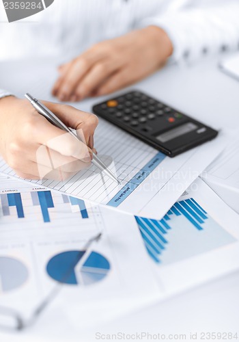 Image of woman hand with calculator and papers