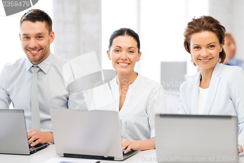 Image of group of people working with laptops in office