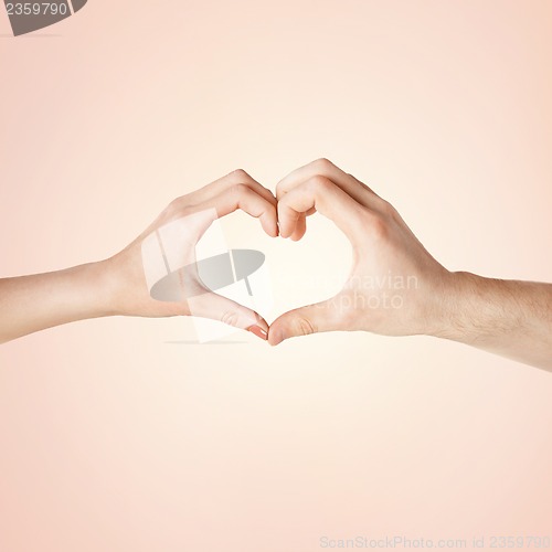 Image of woman and man hands showing heart shape