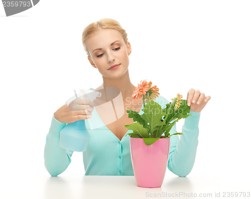 Image of woman holding pot with flower and spray bottle