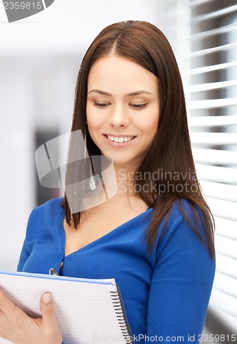 Image of smiling young businesswoman with notebook