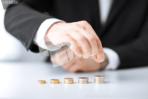 Image of man putting stack of coins into one row