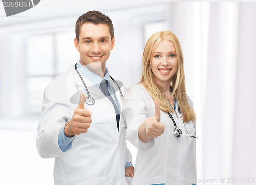 Image of young team of two doctors showing thumbs up