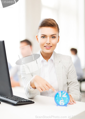 Image of businesswoman pointing at clock in office