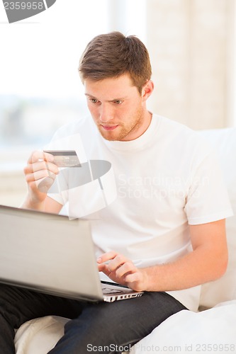 Image of man with laptop and credit card at home