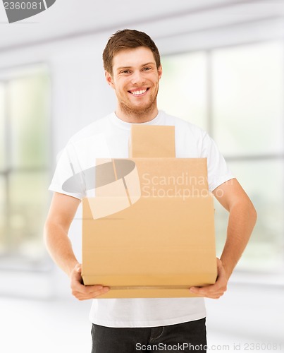 Image of smiling man carrying carton boxes at home