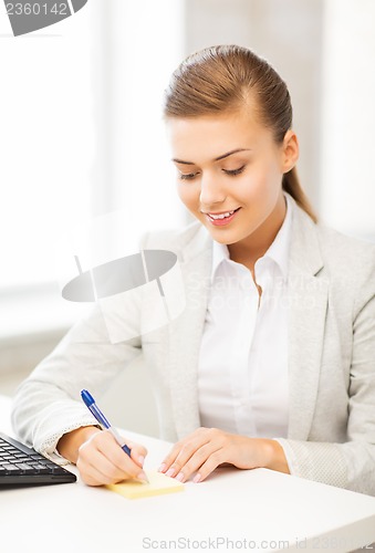 Image of businesswoman writing on sticky note