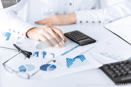 Image of woman hand with calculator and papers