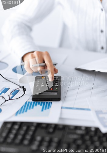 Image of woman hand with calculator and papers