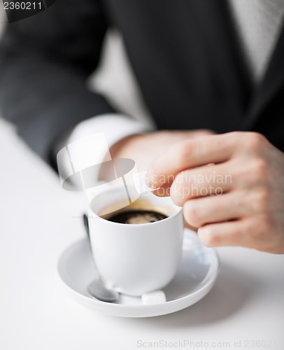 Image of man putting sugar into coffee