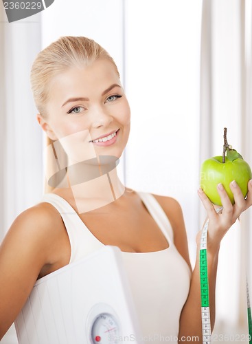 Image of sporty woman with scale, apple and measuring tape