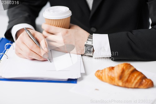 Image of businessman with coffee writing something