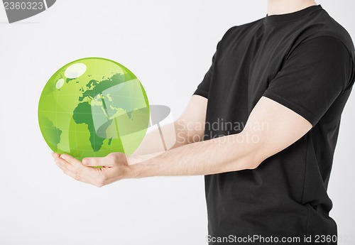 Image of man holding green sphere globe