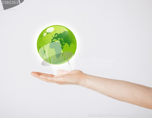 Image of mans hand holding green globe