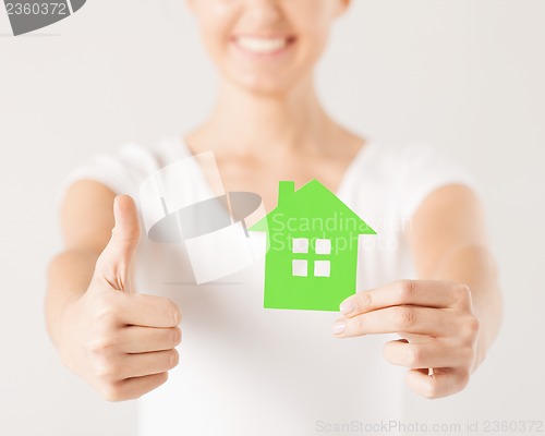 Image of woman hands holding green house