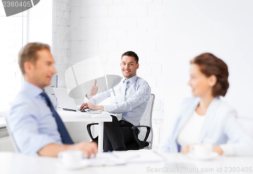 Image of happy businessman showing thumbs up in office