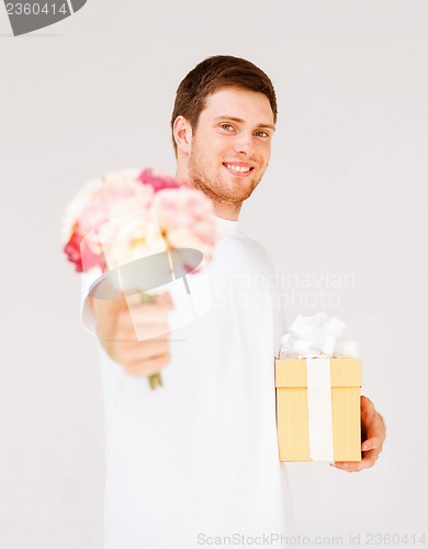 Image of man holding bouquet of flowers and gift box