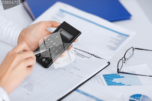 Image of woman hand with calculator and papers