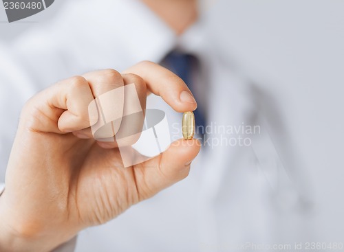 Image of doctor hand showing one capsule