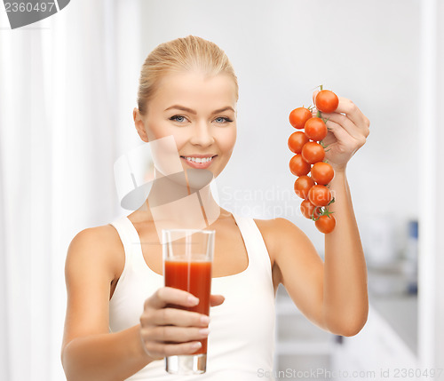 Image of woman holding glass of juice and tomatoes